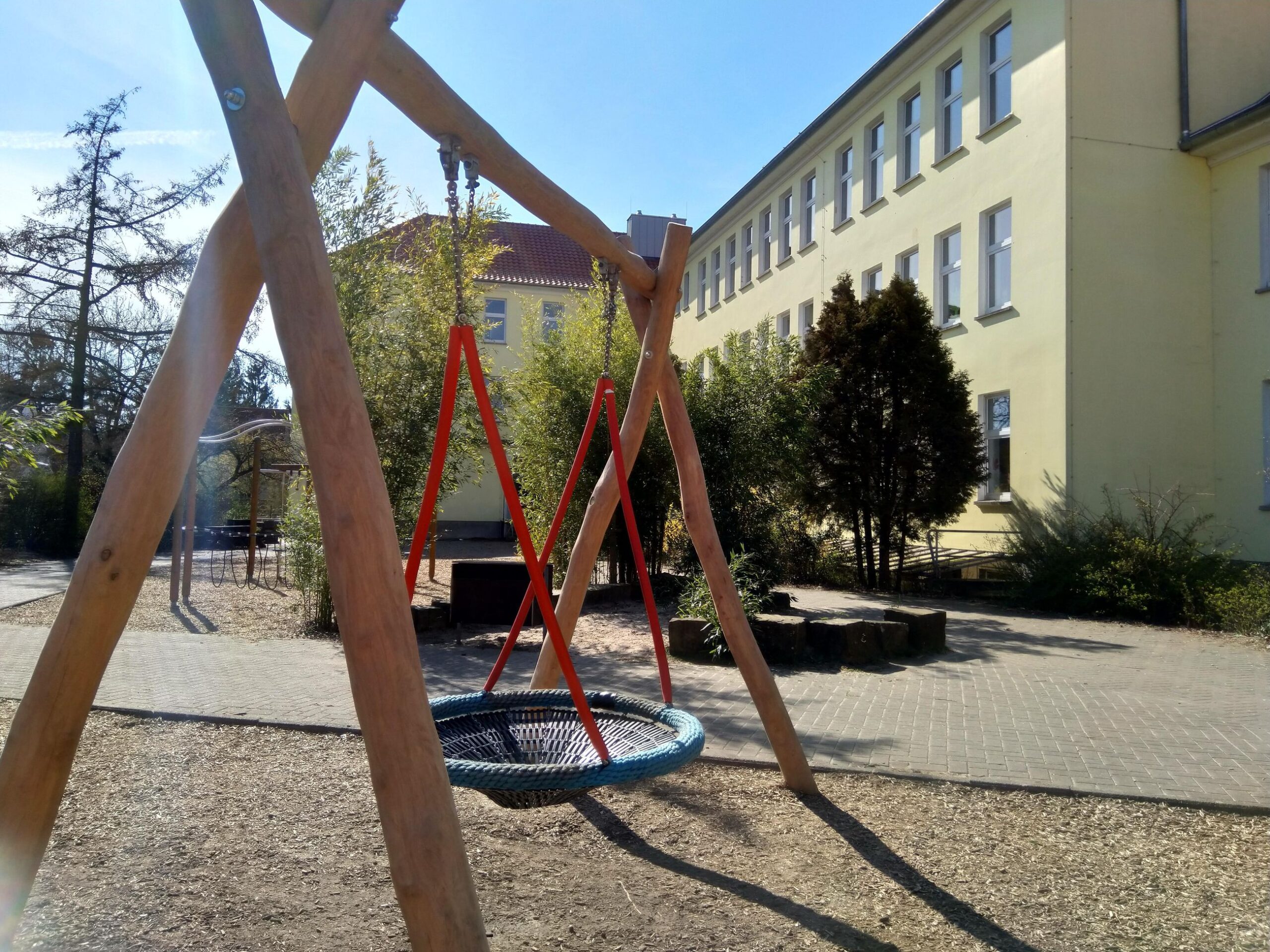 Spielplatz mit neuer Nestschaukel vor dem Schulgebäude